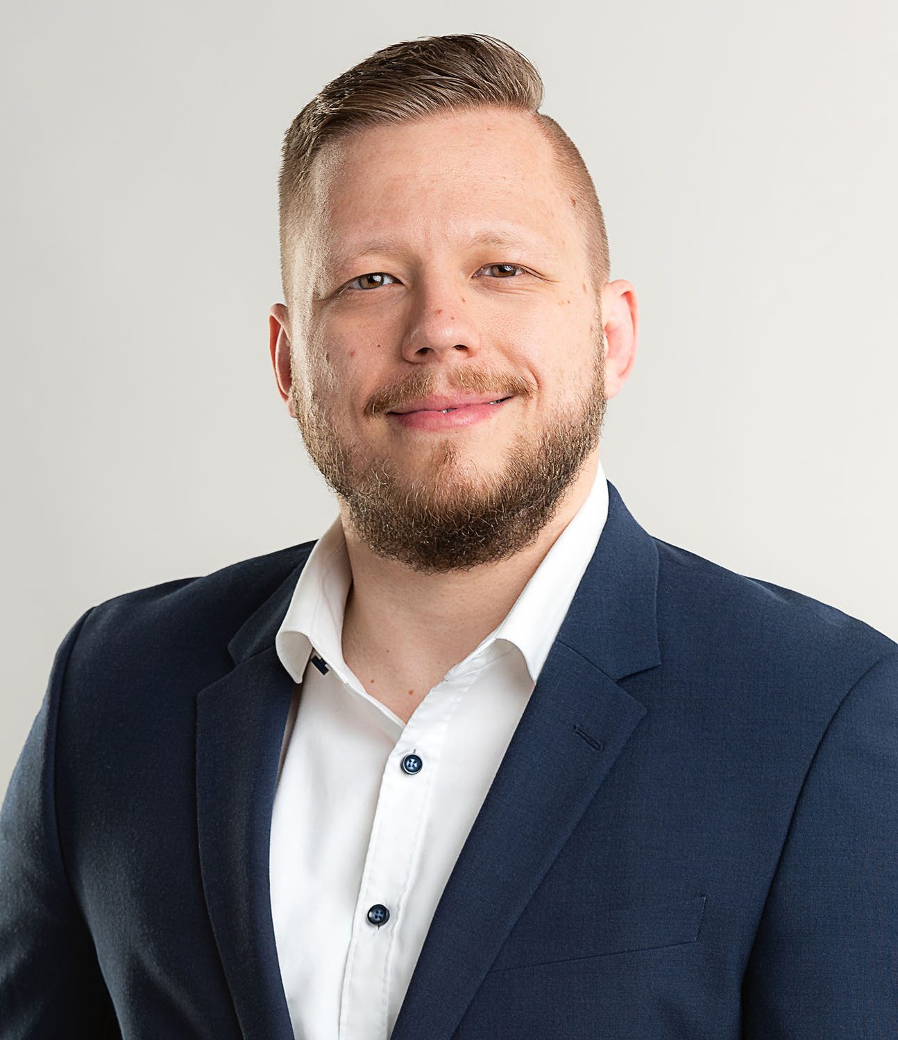 Authentisches Bewerbungsfoto eines Mannes in Business-Kleidung und hellem Hintergrund.